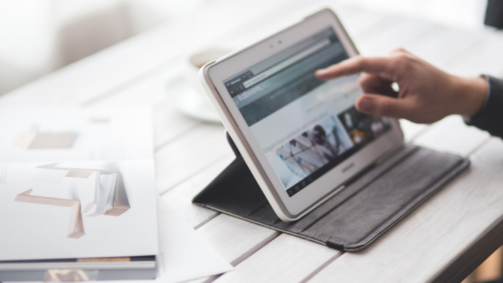 Profissional utilizando tablet e notebook para gerenciar blog como empresa digital