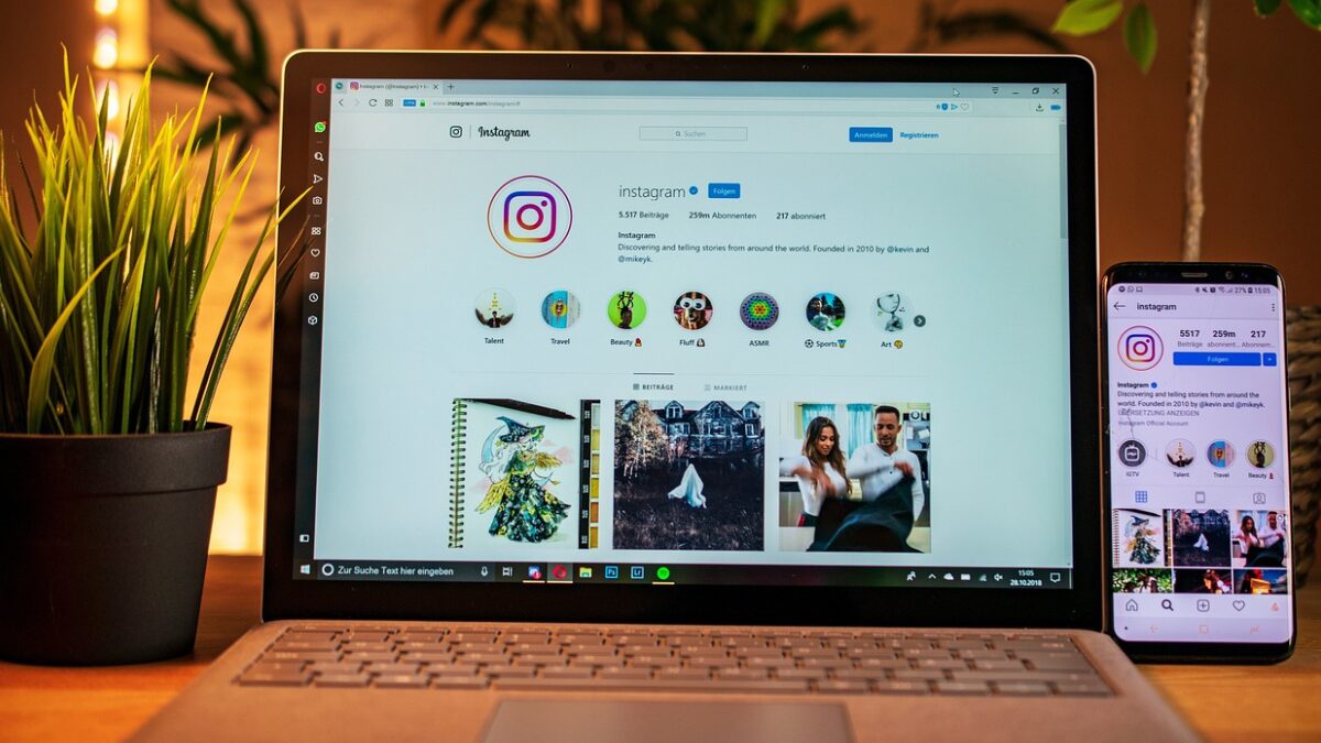 Notebook aberto exibindo um perfil do Instagram com foco na aba de Reels, ao lado de um smartphone mostrando a mesma interface.