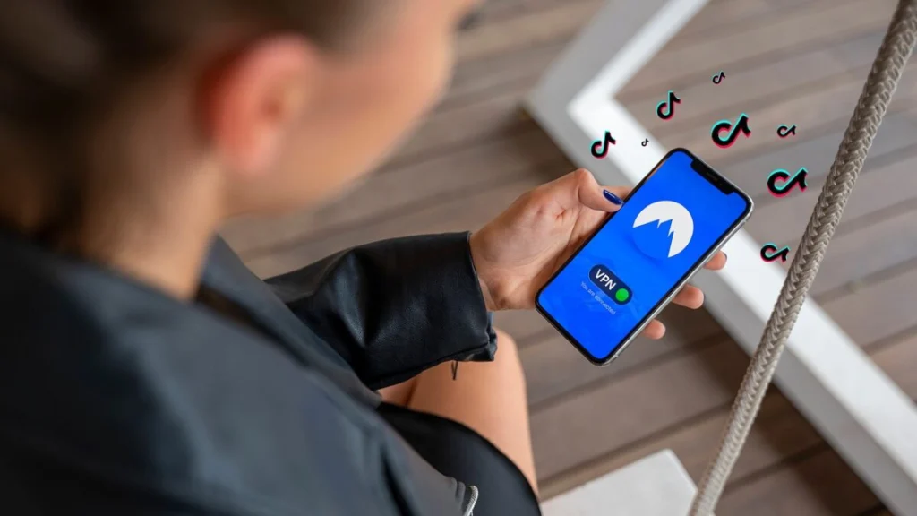 Visão aérea de uma pessoa segurando um smartphone com o aplicativo TikTok aberto, focando na interface de vídeos da rede social.